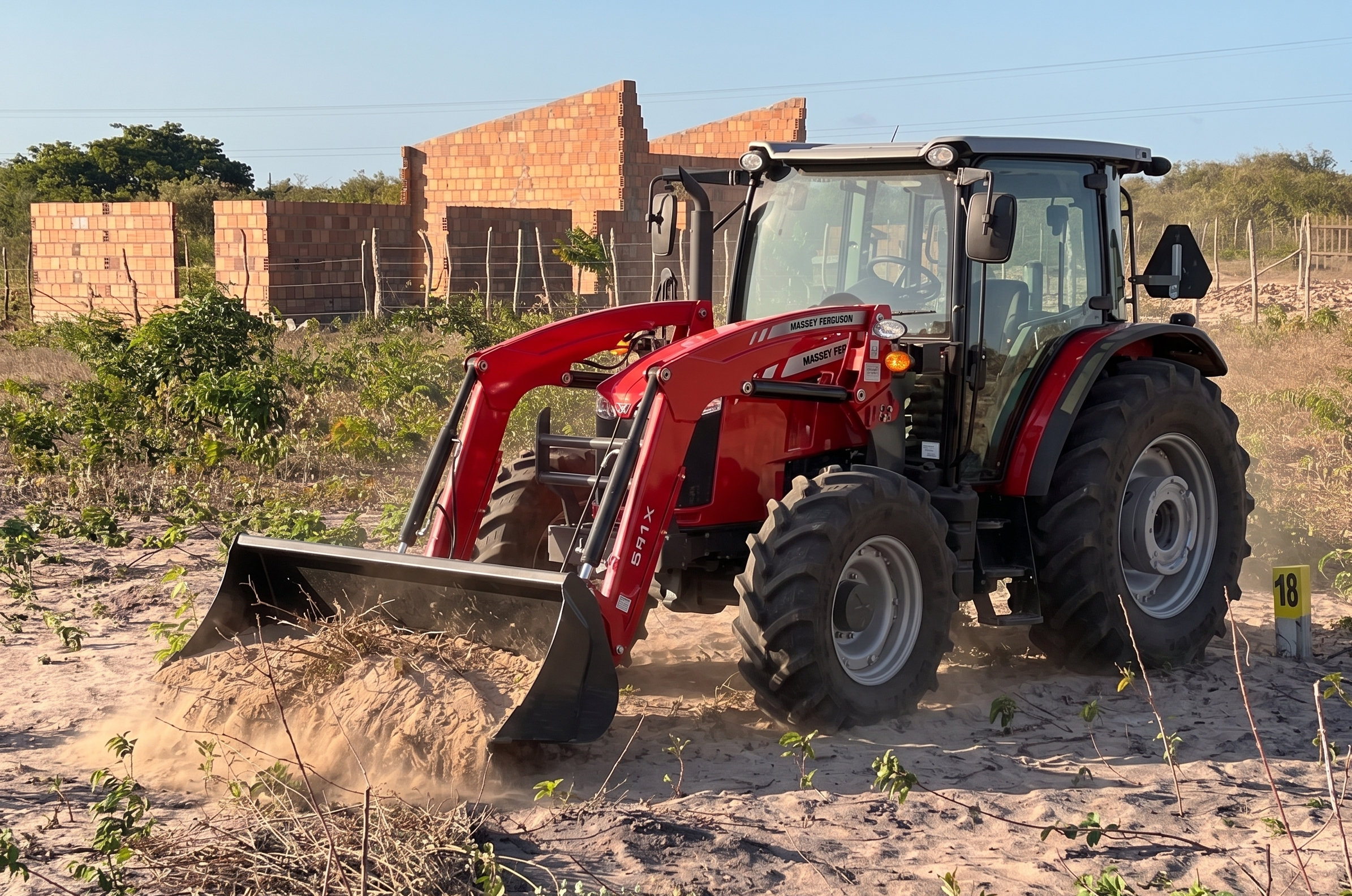 Trator realizando limpeza de terreno com construção ao fundo em Trairi/CE